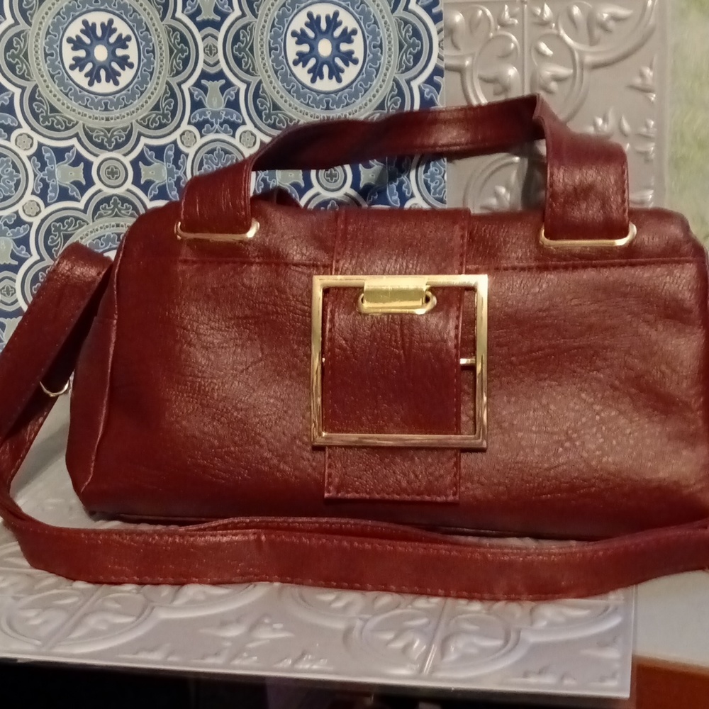 Boho style purse in  burgundy with large gold buckle and hardware.